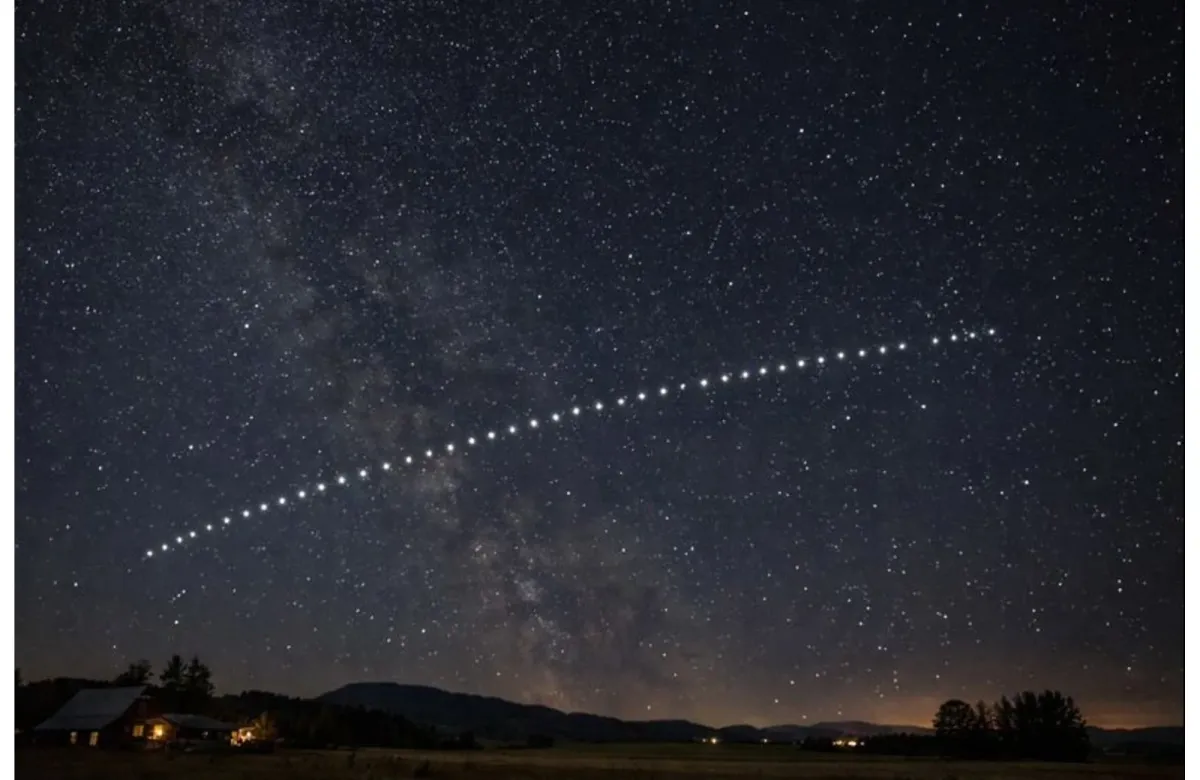 Starlink satellites appearing in a straight line across the night sky above a rural area.