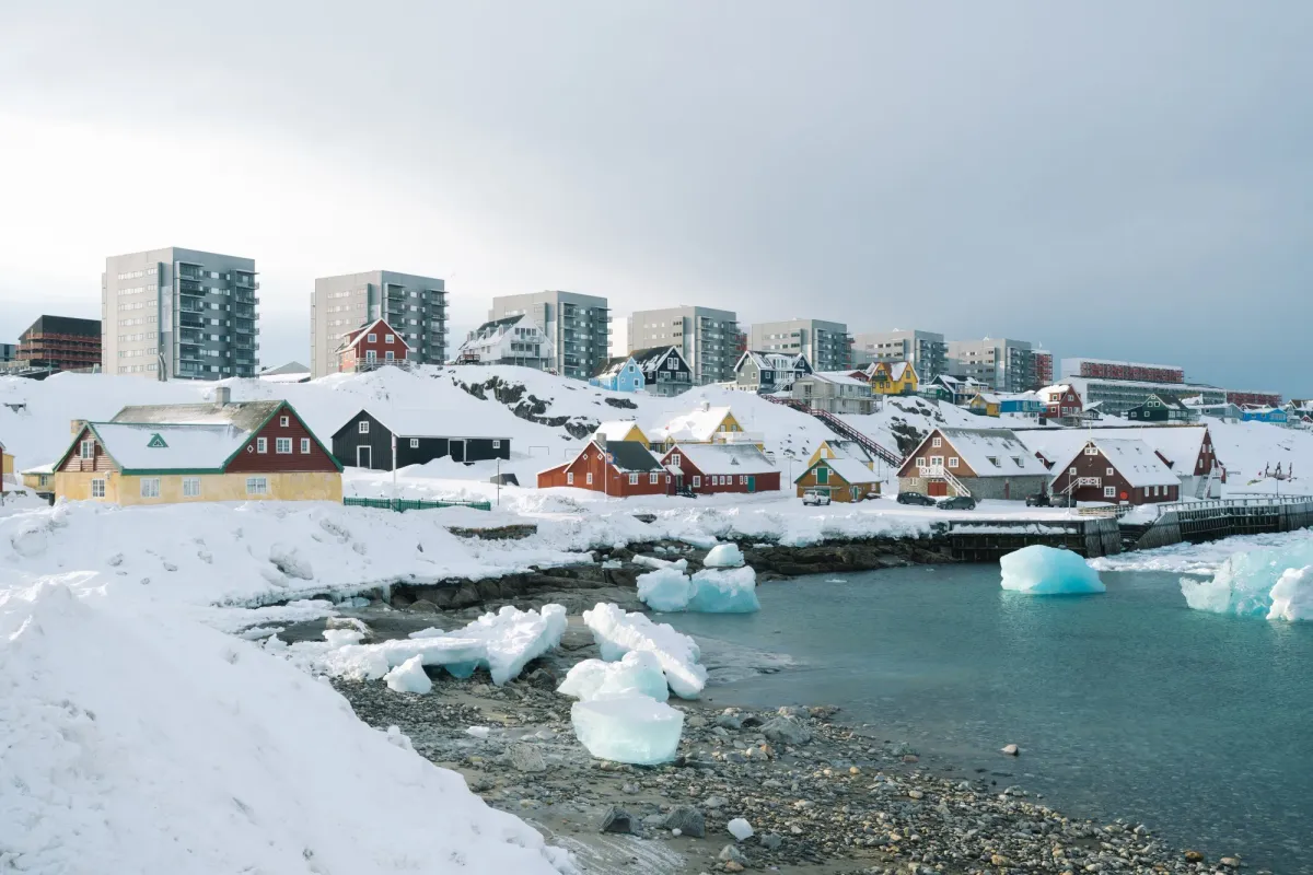 Arctic city in winter with snow-covered buildings and reduced lighting, showing how power outages affect daily life in extreme cold.