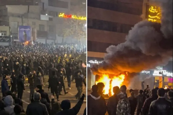 Crowds gather during nighttime protests in Tehran as fire and smoke rise from a damaged building